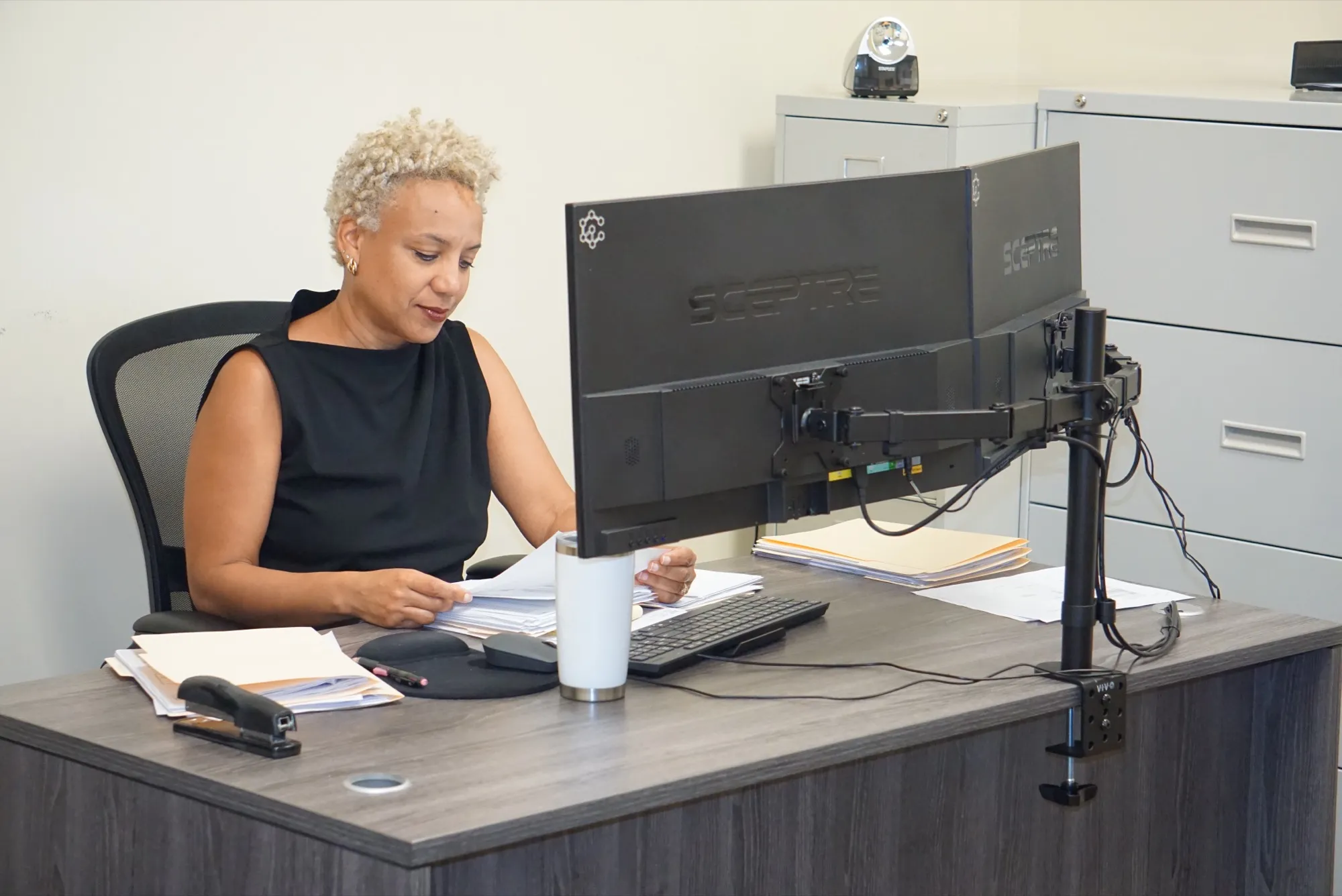 Office staff working at a dual-monitor workstation running the Seneca ERP system